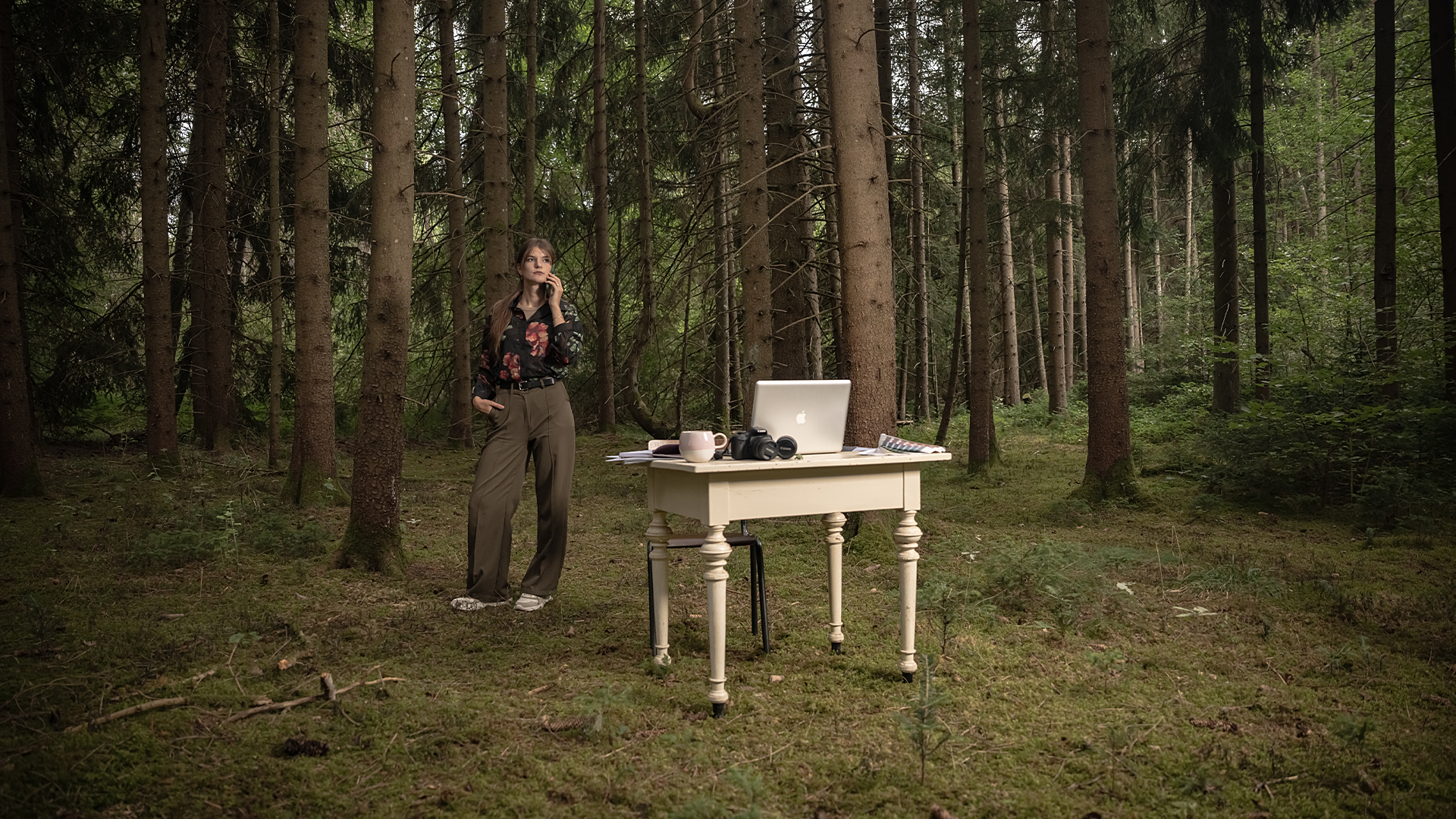 Nadine arbeitet an einem Schreibtisch mit Papier, Skizzen und Gestaltungsmaterialien
